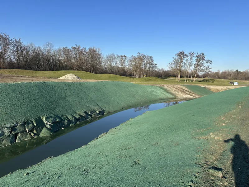 Teich auf einem Golfplatz mit frisch angespritzten, grünen Uferböschungen